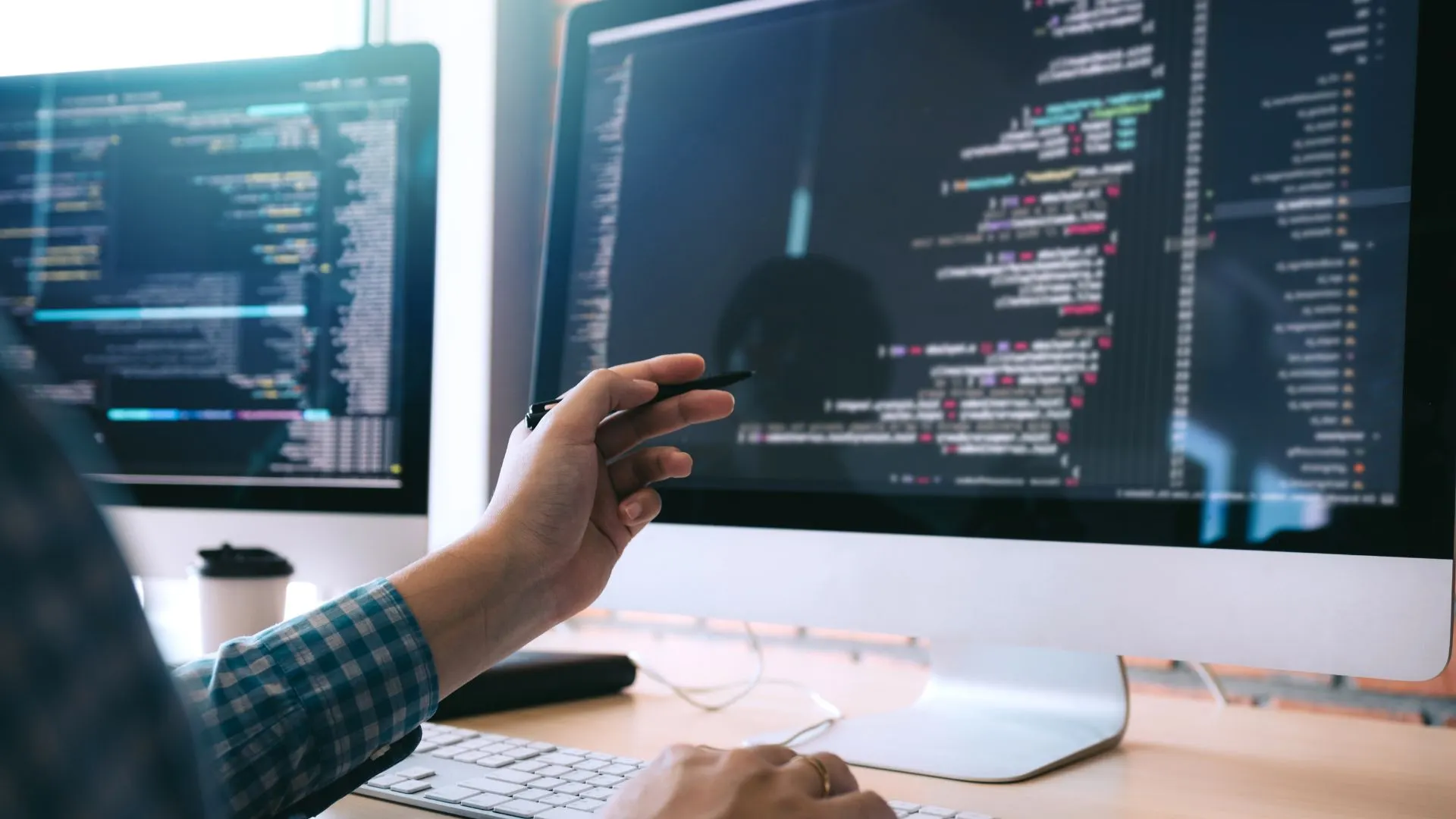 A software developer reviewing code on dual monitors while choosing a backend stack for a new application